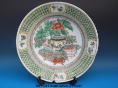 A 19thC Chinese famille verte charger with central scene of flowers in a vase and other objects