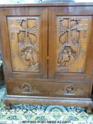 A Chinese elm desk with carved door panels to the cupboard depicting a couple by pergoda over