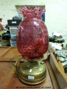 A brass oil lamp converted to electricity with cranberry shade (h51cm)