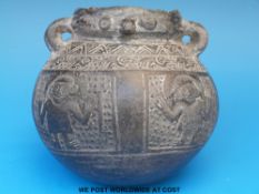 A pre-Columbian Peruvian Chimu pottery vessel with two small ring handles, decorated with figures,