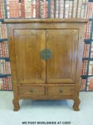 A Chinese elm two door cabinet with drawers under, raised on shaped front legs,