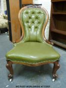 A Victorian walnut carved spoon back button upholstered nursing chair with scroll turned ends,