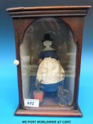 A wooden and ceramic doll in display case,