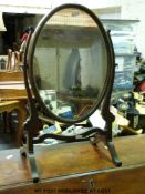 A mahogany oval dressing table mirror on scroll feet (height 55cm)