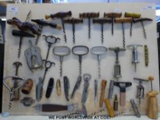 A collection of 19thC and later corkscrews mounted on a display board,