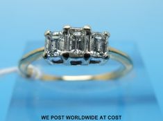 An 18ct gold ring set with three emerald cut diamonds, approximately 0.