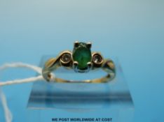 A yellow metal ring marked 9ct gold set with an oval emerald surrounded flanked by diamonds (size