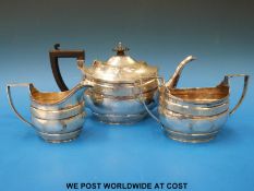 An Edwardian hallmarked silver Georgian style three piece teaset with engraved decoration,