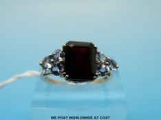 A 10ct gold ring set with a garnet flanked by purple stones (size N)