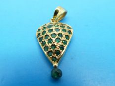 A yellow metal pendant set with emeralds
