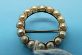 A gold circular seed pearl brooch