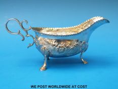 A Georgian hallmarked silver, sauce boat with embossed decoration, raised on three hoof feet,