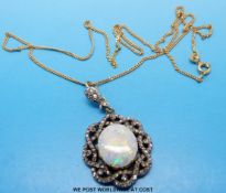 An 18ct gold and platinum pendant set with a large opal surrounded by old cut diamonds on an 18ct