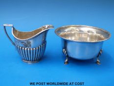 A hallmarked silver sugar bowl with gadrooned edge together with a silver cream jug with fluted