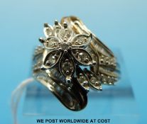 A yellow metal and white metal ring set with baguette and round brilliant cut diamonds in a floral