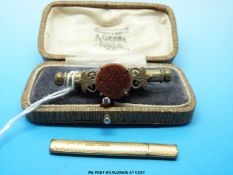 A yellow metal needle case marked 15ct and a cased brass brooch/needle case set with a sunstone