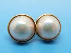 A pair of yellow metal earrings each set with a mingle Mabe pearl