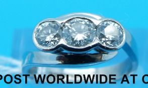 A platinum ring set with three round brilliant cut diamonds in a rub over twist setting,