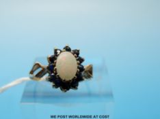 A 9ct gold ring set with an opal cabochon surrounded by sapphires (size L)