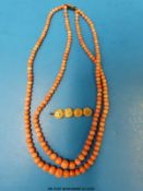 A gold brooch decorated with Chinese characters and a two strand coral necklace