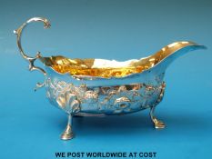 A Georgian hallmarked silver sauce boat with gilt wash interior and embossed decoration raised on