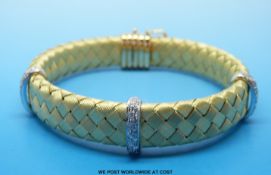 An 18ct gold bracelet of woven design with three white gold diamond set bands,