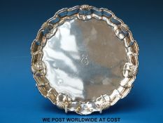 A Mappin & Webb George V hallmarked silver salver with shaped edge, raised on three scrolling feet,