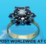 An 18ct gold ring set with sapphires and a central diamond in a flower cluster (size M)