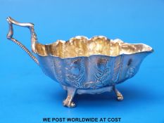 A Georgian hallmarked silver cream jug with gilt wash interior and embossed decoration, Ldn 1767,