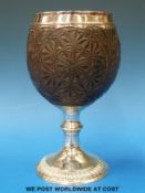 A Georgian white metal-mounted carved coconut with pedestal base and white metal rim,