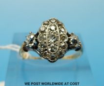 An Art Deco 18ct gold ring set with 15 old cut diamonds in an oval setting flanked by a diamond to