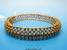A yellow metal bangle of lattice design with small raised gold spheres (unmarked but possibly 22ct,