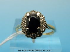 An 18ct gold ring set with an oval sapphire surrounded by diamonds (size S)