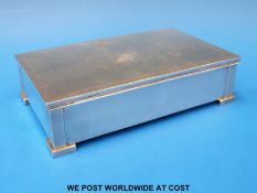 An Art Deco hallmarked silver cigarette box with engine-turned decoration raised on four L-shaped