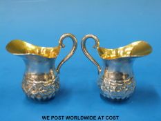 A pair of miniature embossed white metal jugs with gilt wash interiors each marked 800 and 32 under