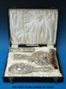 A cased and wrapped embossed hallmarked silver four-piece dressing table set