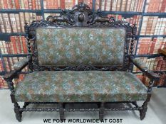 A Victorian carved oak settle with lion pediment raised on eight legs joined by bobbin turned