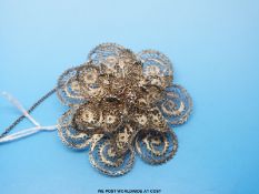 A white metal filigree brooch in a flower design