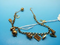A yellow metal charm bracelet with overseas hallmarks and 11 charms,