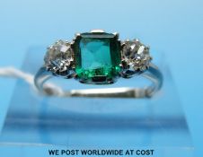 A white metal ring set with a square cut emerald of approximately 0.
