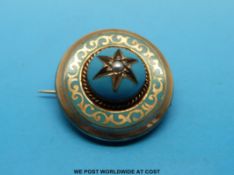 A gold brooch with blue enamel and a seed pearl to the centre and compartment to the back