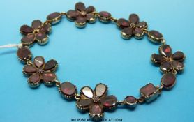 A Victorian yellow metal bracelet made up of six garnet set flower links
