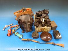 A collection of bakelite plugs, switches and binoculars, a wooden dog's head and a small tin,