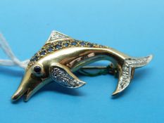 A 9ct gold brooch set with sapphires and diamonds in the shape of a dolphin