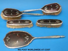 A hallmarked silver and tortoiseshell dressing table set comprising hand mirror and four various