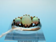 A gold ring set with an oval opal flanked by two round (size L)