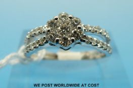 An 18ct white gold ring set with seven diamonds in a cluster with diamond encrusted shoulders (size