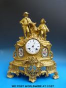 A two train brass mantel clock with Sevres style panels and two figures to the top.
