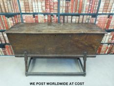 An antique elm dough bin with hinged lid, raised on turned legs united by moulded stretchers (H76,