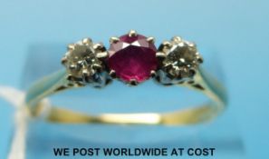 An 18ct gold ring set with a ruby flanked by diamonds (size S)